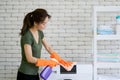 Asian housewife wearing rubber gloves, use a spray and cloth to clean the washing machine. Working atmosphere in the laundry room