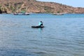 Asian Indonesian male riding and sailing small boat floating on the ocean, one person transporting over the sea