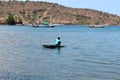 Asian Indonesian male riding and sailing small boat floating on the ocean, one person transporting over the sea