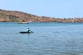 Asian Indonesian male riding and sailing small boat floating on the ocean, one person transporting over the sea