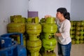 Asian Indonesian women arranging 3Kg gas cylinders inside small local family-owned business store, locally called warung.