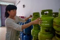 Asian Indonesian women arranging 3Kg gas cylinders inside small local family-owned business store, locally called warung.