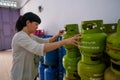 Asian Indonesian women arranging 3Kg gas cylinders inside small local family-owned business store, locally called warung.