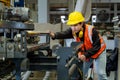 Asian industrial worker is checking setup value of metal sheet roll forming machine inside roof factory for safety industry Royalty Free Stock Photo