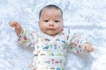 Asian Infant baby is ralaxing on the white bed. It is watching at me. It`s face is frown. Royalty Free Stock Photo