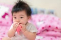 Asian Infant girl biting teether, baby growing first tooth Royalty Free Stock Photo