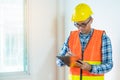 Asian inspector checking structure of new property and taking note in the clipboard for review and fix the house before sell. Royalty Free Stock Photo