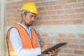 Asian inspector checking structure of new property and taking note in the clipboard for review and fix the house before sell to Royalty Free Stock Photo