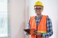 Asian inspector checking structure of new property and taking note in the clipboard for review and fix the house. Royalty Free Stock Photo