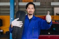 Asian Japanese male mechanic worker portrait in auto service workshop car tyre maintenance center replace fix auto part Royalty Free Stock Photo
