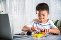 Asian kid boy assembling the Arduino robot car homework project at home