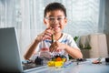 Asian kid boy assembling the Arduino robot car homework project at home