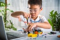 Asian kid boy assembling the Arduino robot car homework project at home