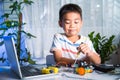 Asian kid boy assembling the Arduino robot car homework project at home