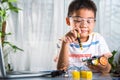 Asian kid boy assembling the Arduino robot car homework project at home