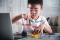 Asian kid boy assembling the Arduino robot car homework project at home