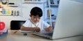 Asian Kid Boy Focused on Homework and Learning Alone in Room at Home, Serious Asian Kid Concentrating on Homework, Studying and Royalty Free Stock Photo