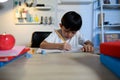 Asian Kid Boy Focused on Homework and Learning Alone in Room at Home, Serious Asian Kid Concentrating on Homework, Studying and Royalty Free Stock Photo