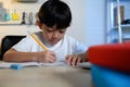 Asian Kid Boy Focused on Homework and Learning Alone in Room at Home, Serious Asian Kid Concentrating on Homework, Studying and Royalty Free Stock Photo