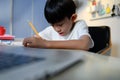 Asian Kid Boy Focused on Homework and Learning Alone in Room at Home, Serious Asian Kid Concentrating on Homework, Studying and Royalty Free Stock Photo