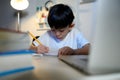 Asian Kid Boy Focused on Homework and Learning Alone in Room at Home, Serious Asian Kid Concentrating on Homework, Studying and Royalty Free Stock Photo