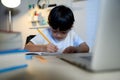 Asian Kid Boy Focused on Homework and Learning Alone in Room at Home, Serious Asian Kid Concentrating on Homework, Studying and Royalty Free Stock Photo