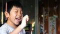 Asian kid child boy with pencil on ear sing song with relax face to build power before doing school exercise homework at home.