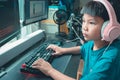 Asian kid coding and scripting program on on his game streaming desktop computer with headphone on