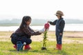 Asian  kid daughter helping mother water the plant and sapling tree outdoors in nature spring for reduce global Royalty Free Stock Photo