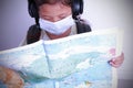 Asian kid girl carrying travel backpack holding maps world wearing a mask on white background