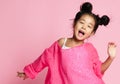 Asian kid girl in pink sweater, white pants and funny buns sings. close up. Royalty Free Stock Photo