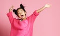 Asian kid girl in pink sweater, white pants and funny buns sings singing dancing on pink