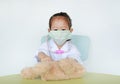 Asian Kid girl with protect mask plays doctor with her bear doll Royalty Free Stock Photo