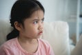 Asian kid girl upset lonely bullied little looking away feels abandoned abused, sad alone sitting on the sofa couch in living room Royalty Free Stock Photo