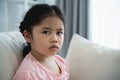 Asian kid girl upset lonely bullied little looking at camera feels abandoned abused, sad alone sitting on the sofa couch in living Royalty Free Stock Photo