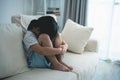 Asian kid girl upset lonely bullied little Sitting hugging your knees on the sofa couch in living room at home feels abandoned Royalty Free Stock Photo