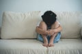 Asian kid girl upset lonely bullied little Sitting hugging your knees on the sofa couch in living room at home feels abandoned Royalty Free Stock Photo