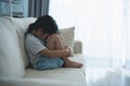 Asian kid girl upset lonely bullied little Sitting hugging your knees on the sofa couch in living room at home feels abandoned Royalty Free Stock Photo