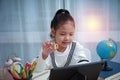 Asian kid girls learn mathematics online at home.