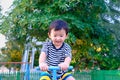 Asian kid riding seesaw board at the playground under sunlight,