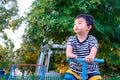 Asian kid riding seesaw board at the playground under sunlight,