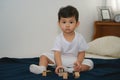 Asian kid sitting on bed playing letter block at home