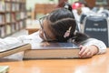 Asian kid student studying hard feeling tired in school library sleeping on big book in library or classroom Royalty Free Stock Photo