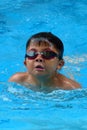 Asian kid swims in swimming pool - butterfly style take deep breath Royalty Free Stock Photo