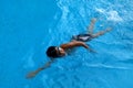 Asian kid swims in swimming pool - front crawl style with power scissor kick Royalty Free Stock Photo