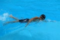 Asian kid swims in swimming pool - front crawl style with power scissor kick