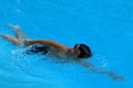 Asian kid swims in swimming pool - front crawl style with power scissor kick Royalty Free Stock Photo