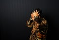 Asian kid wearing Batik holding his head and looks frustrated isolated on black background Royalty Free Stock Photo