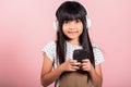 Asian kid 10 years enjoying listening music from mobile phone wear wireless headset Royalty Free Stock Photo