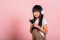 Asian kid 10 years enjoying listening music from mobile phone wear wireless headset closed eyes Royalty Free Stock Photo